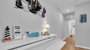 Un intérieur moderne avec une console blanche, une décoration représentant une baleine bleue, un phare et un panneau d’accueil.