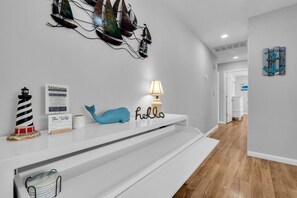 A modern interior with a white console table, a blue whale decoration, a lighthouse, and a welcome sign. - Relaxed Ocean Gate Shore Getaway 3BR + Fireplace (Ocean Gate)
