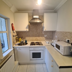 A kitchen with white cabinets, a stove, a microwave, and a tiled backsplash.