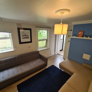 A living room with a sofa, a smaller couch, a floor lamp, and a window with blinds. - Private Apartment (Flat 2) (Dublin)