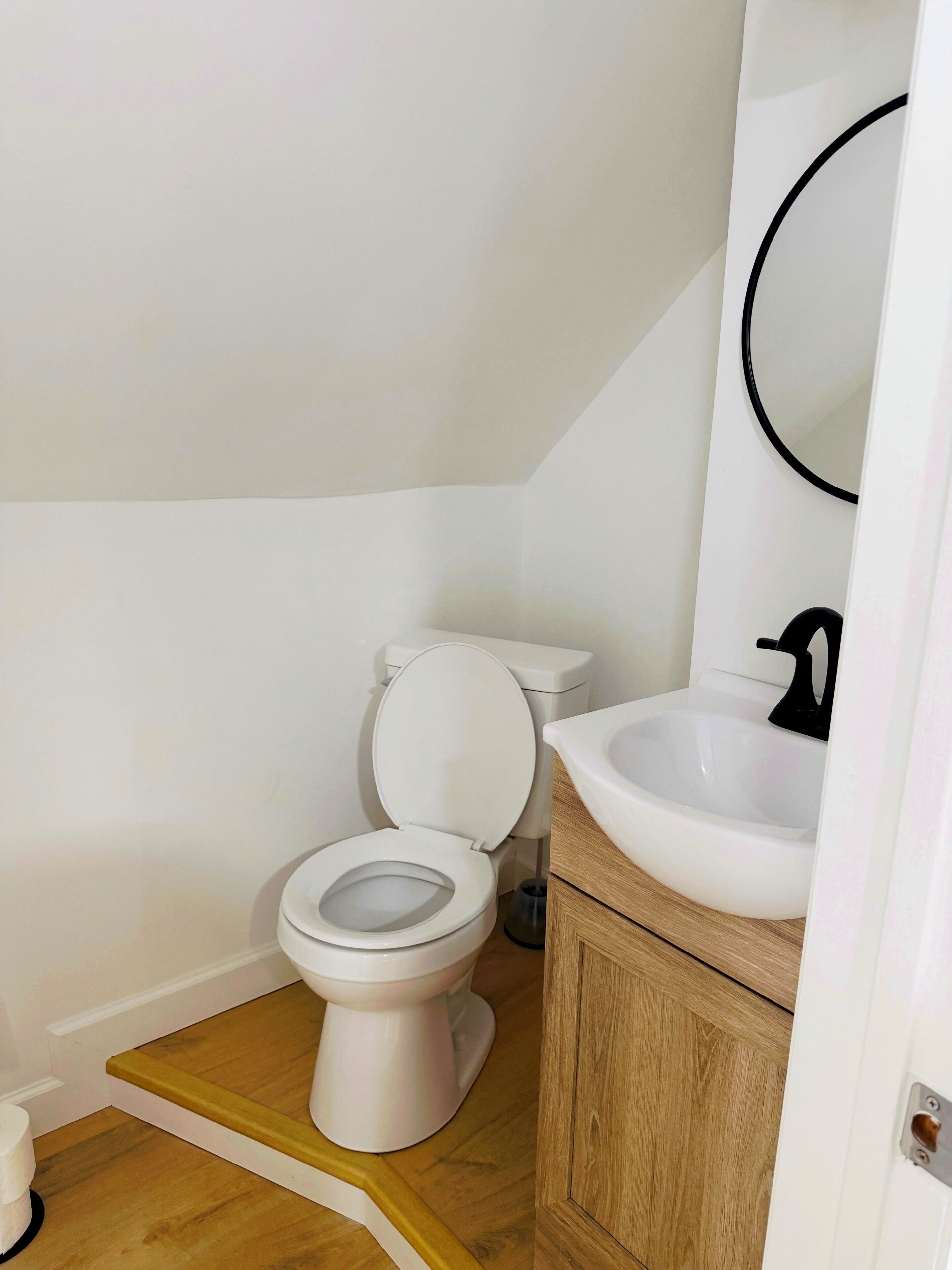 A small bathroom with a toilet, sink, and mirror.