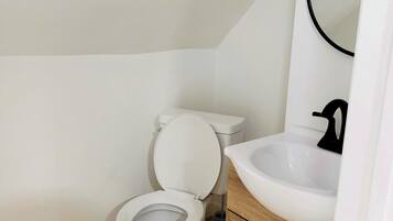 A small bathroom with a toilet, sink, and mirror.