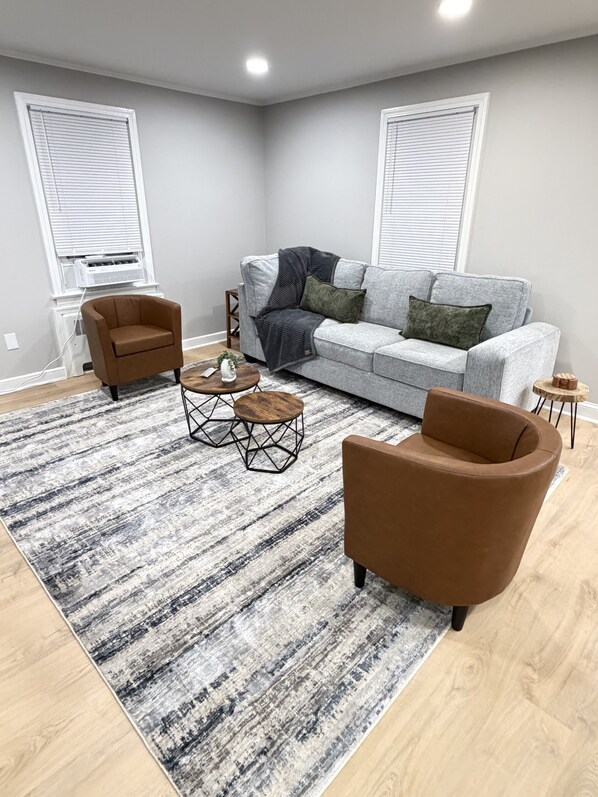 A living room with a grey sofa, two brown armchairs, a coffee table, and a patterned rug.