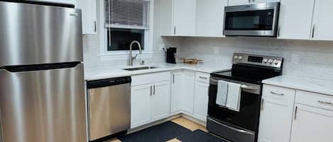 A modern kitchen with white cabinets, stainless steel appliances, and a black oven.