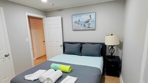Une chambre d’hôtel avec un lit, un tableau au mur, une lampe de chevet et une porte.