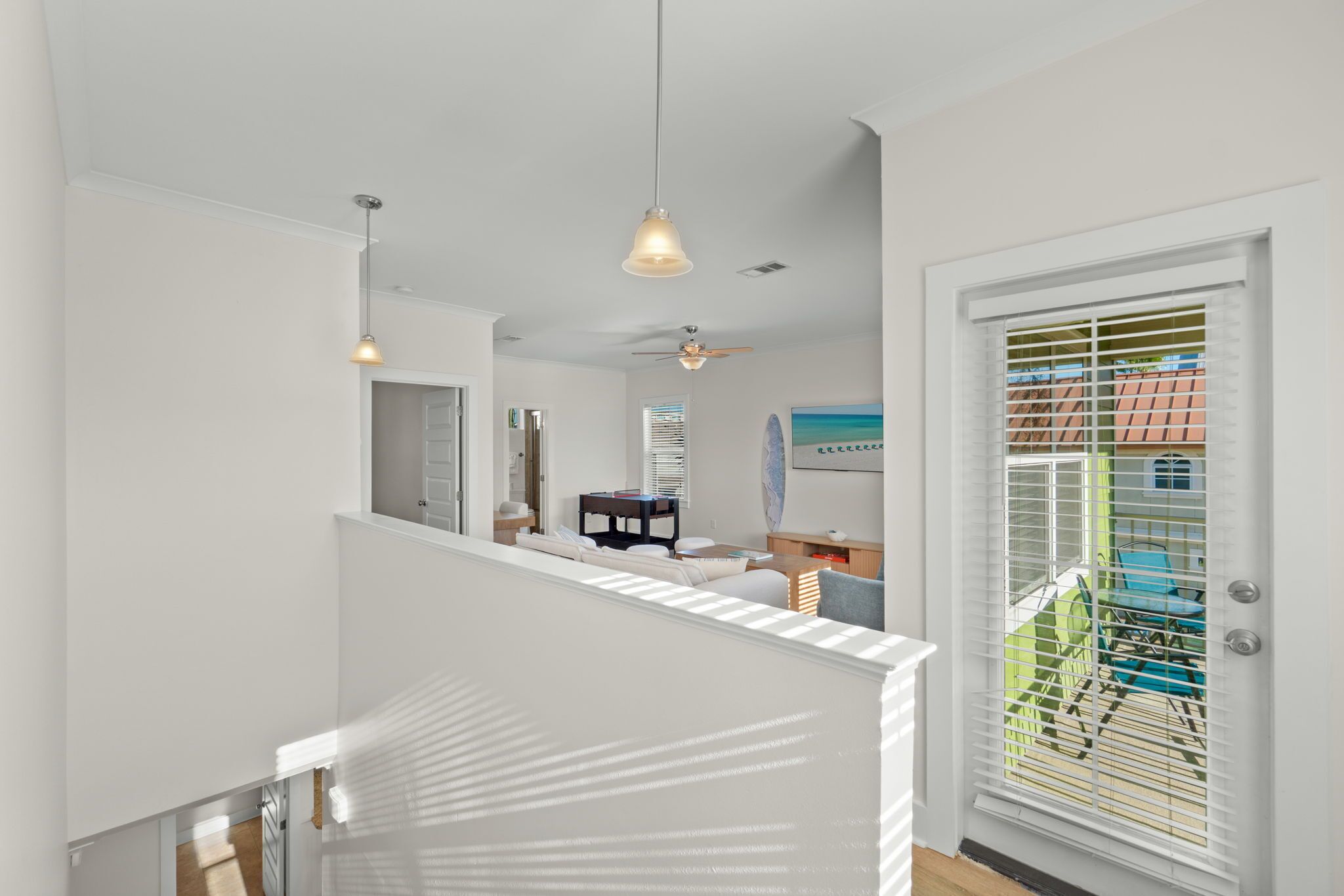 A modern interior with a staircase, a ceiling fan, and a view of the outside through a window with blinds.