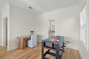 A room with a foosball table, a desk, and a chair. - Sleeps 10 l 3 Min to Beach l Pool l Game Room l Wireless Internet l Pompano Joes (Miramar Beach)
