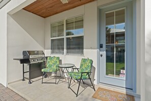 A patio with a grill, two chairs, and a door with a security camera warning. - Sleeps 10 l 3 Min to Beach l Pool l Game Room l Wireless Internet l Pompano Joes (Miramar Beach)