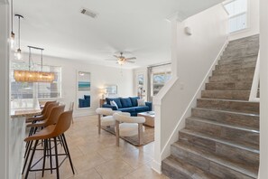 A modern interior with a staircase, a dining area, and a living room with a blue sofa. - Sleeps 10 l 3 Min to Beach l Pool l Game Room l Wireless Internet l Pompano Joes (Miramar Beach)