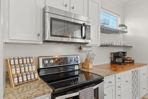 A kitchen with a stainless steel microwave, oven, and a spice rack. - Sleeps 10 l 3 Min to Beach l Pool l Game Room l Wireless Internet l Pompano Joes (Miramar Beach)