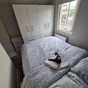 A bedroom with a bed, a radiator, a window, and a wardrobe. - Private Apartment (Flat 3) (Dublin)