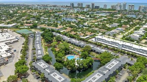 Vista aérea de una zona residencial con piscina central rodeada de abundante vegetación y conectada a un puerto deportivo.