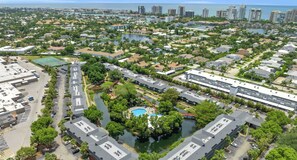 An aerial view of a residential area with a central swimming pool surrounded by lush greenery and connected to a marina. - D-226 - Peaceful Views on Quiet End of Resort (Naples)