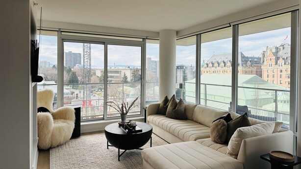 Ein modernes Wohnzimmer mit großem Fenster, einer Couch, einem Sessel und einem Couchtisch.