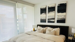 Une chambre à coucher avec un grand lit, une table de chevet, une lampe et une fenêtre donnant sur un beau paysage.