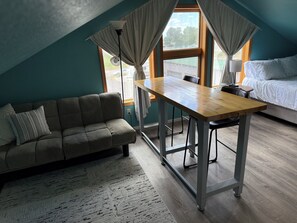 A cozy room with a sofa, a dining table, and a bed.