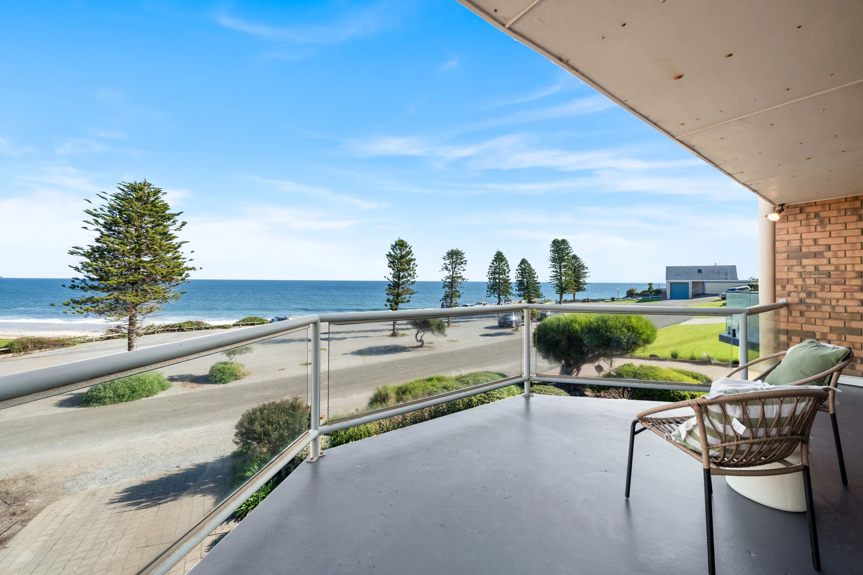 A balcony with a view of the beach and ocean.