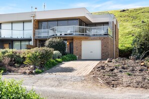 Uma casa moderna de dois andares com varanda, garagem e um jardim ajardinado.