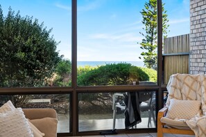 Quarto com uma grande janela com vista para um jardim e o mar.