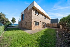 A modern two-story house with a brick exterior, a flat roof, and a small front yard. - Carrickalinga House A Symphony of Sea and Serenity (Carrickalinga)