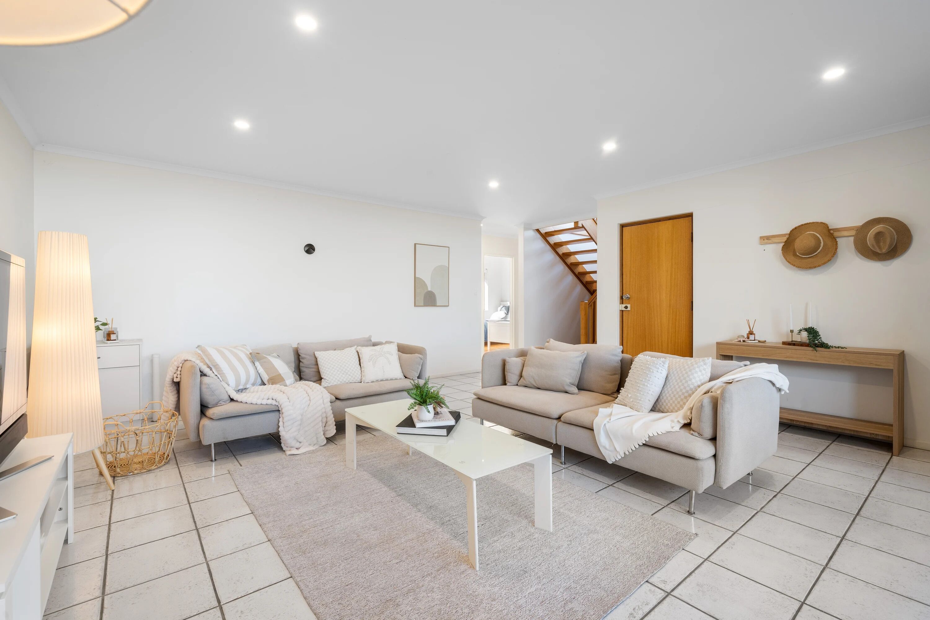 A modern living room with two sofas, a coffee table, and a wooden staircase.