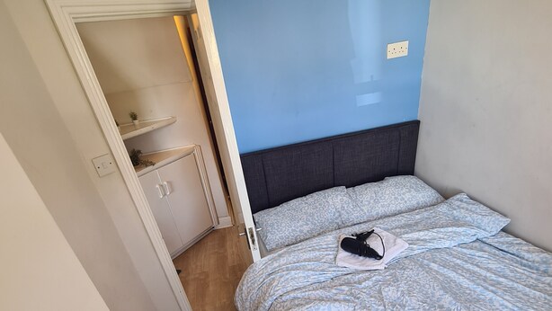 Una camera da letto con un letto, un comodino, un armadio e una parete blu.