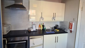 Una cucina compatta con forno a microonde, forno, lavello e pensili.