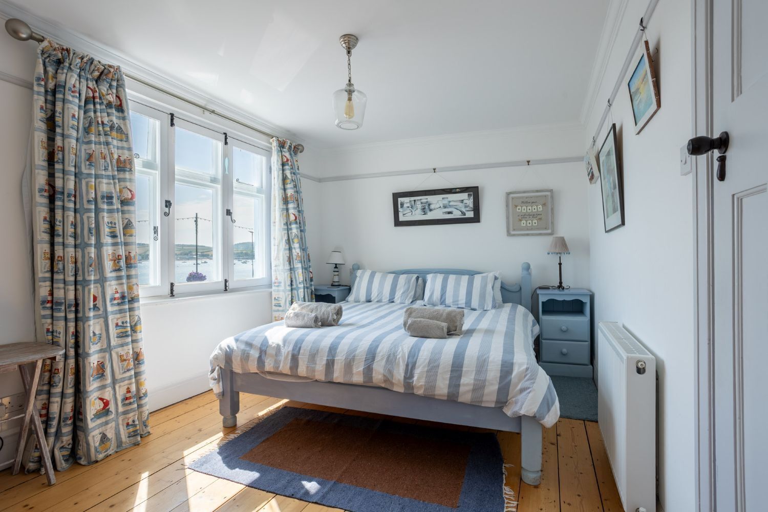 A bedroom with a bed, bedside tables, a radiator, and a window with curtains.