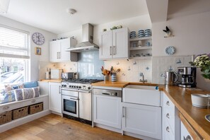 A modern kitchen with white cabinetry, a gas stove, a dishwasher, and a coffee maker. - Quayside retreat with stunning estuary views (Appledore)