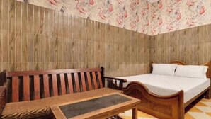 A room with a wooden bed, a wooden bench, and a small table. - Hotel New Lucknow (Lucknow)