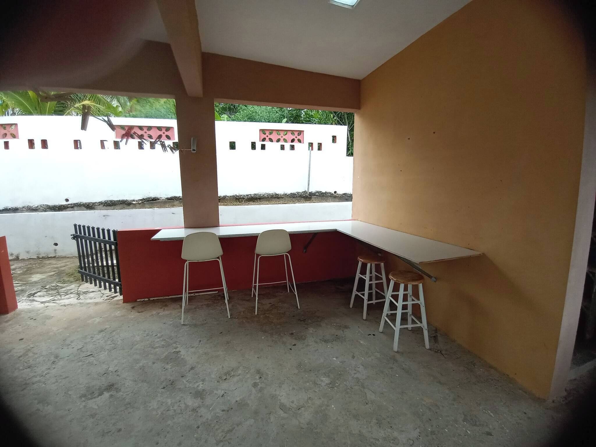 Una habitación con un escritorio blanco, dos sillas y un taburete.