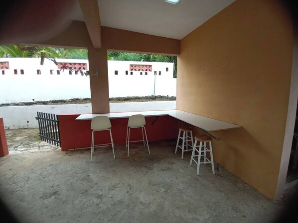 A room with a white desk, two chairs, and a stool.