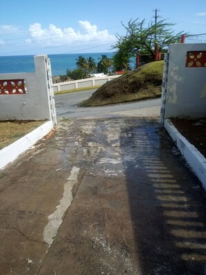 A paved pathway leading to a gated entrance with a view of the ocean. - Spacious Beachfront Escape at Playa Guayanes for Large Groups (Yabucoa)