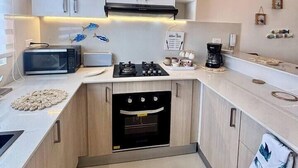Een moderne keuken met witte kastjes, een inbouwoven, een magnetron en een gasfornuis.