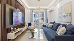Een moderne woonkamer met een flatscreen televisie, een bank, een salontafel en decoratieve objecten.