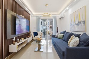 Ein modernes Wohnzimmer mit Flachbildfernseher, einer Couch, einem Couchtisch und Dekorationselementen.