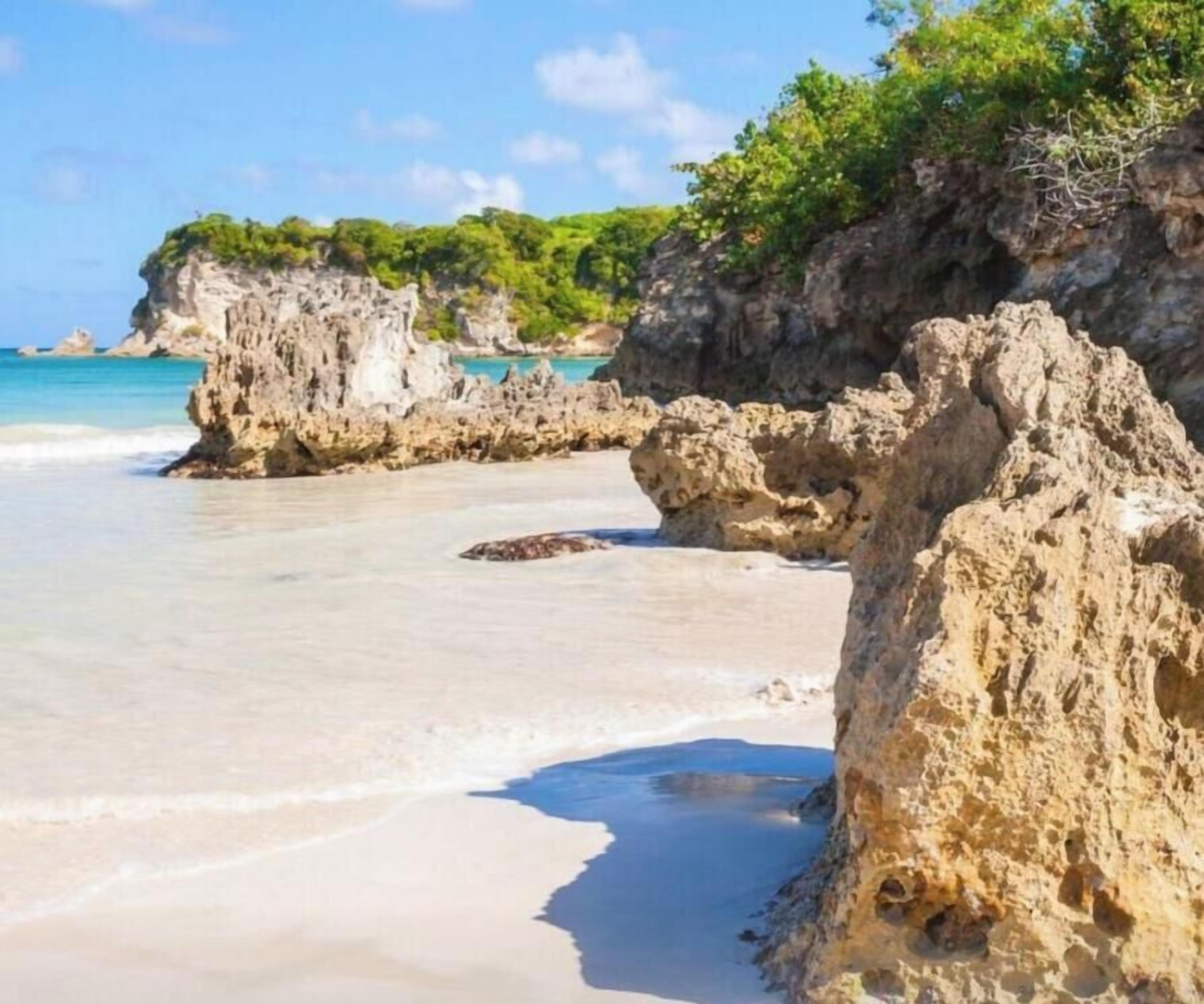 A beach with rocky formations and clear blue water.