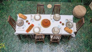 Mesa de comedor lista con platos, cubiertos y pan, rodeada de sillas.