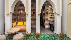 Un patio acogedor con un sofá, cojines, una mesa redonda y faroles decorativos.