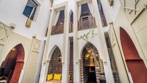 Un edificio con varios balcones, arcos en las puertas y una escalera central.