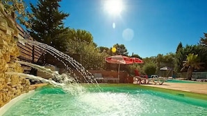 A swimming pool with a water feature and a red umbrella.