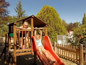 A wooden play structure with a slide and a small shelter. - ZEcamping 3* pataugeoire piscine locatif 5 pers (Junas)