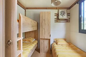Une petite chambre avec des lits superposés et une petite fenêtre.