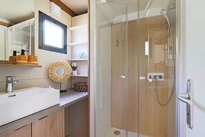 Une salle de bain moderne avec une douche à parois de verre, un lavabo avec un miroir et un meuble-lavabo en bois.
