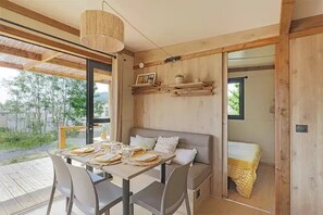 Un coin repas accueillant avec une table dressée pour quatre personnes, un canapé et un luminaire suspendu.