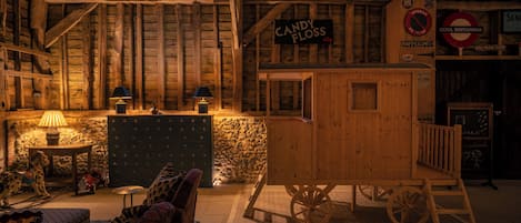 A rustic interior with wooden beams, a candy floss sign, a chalkboard with writing, and a vintage-style seating area.