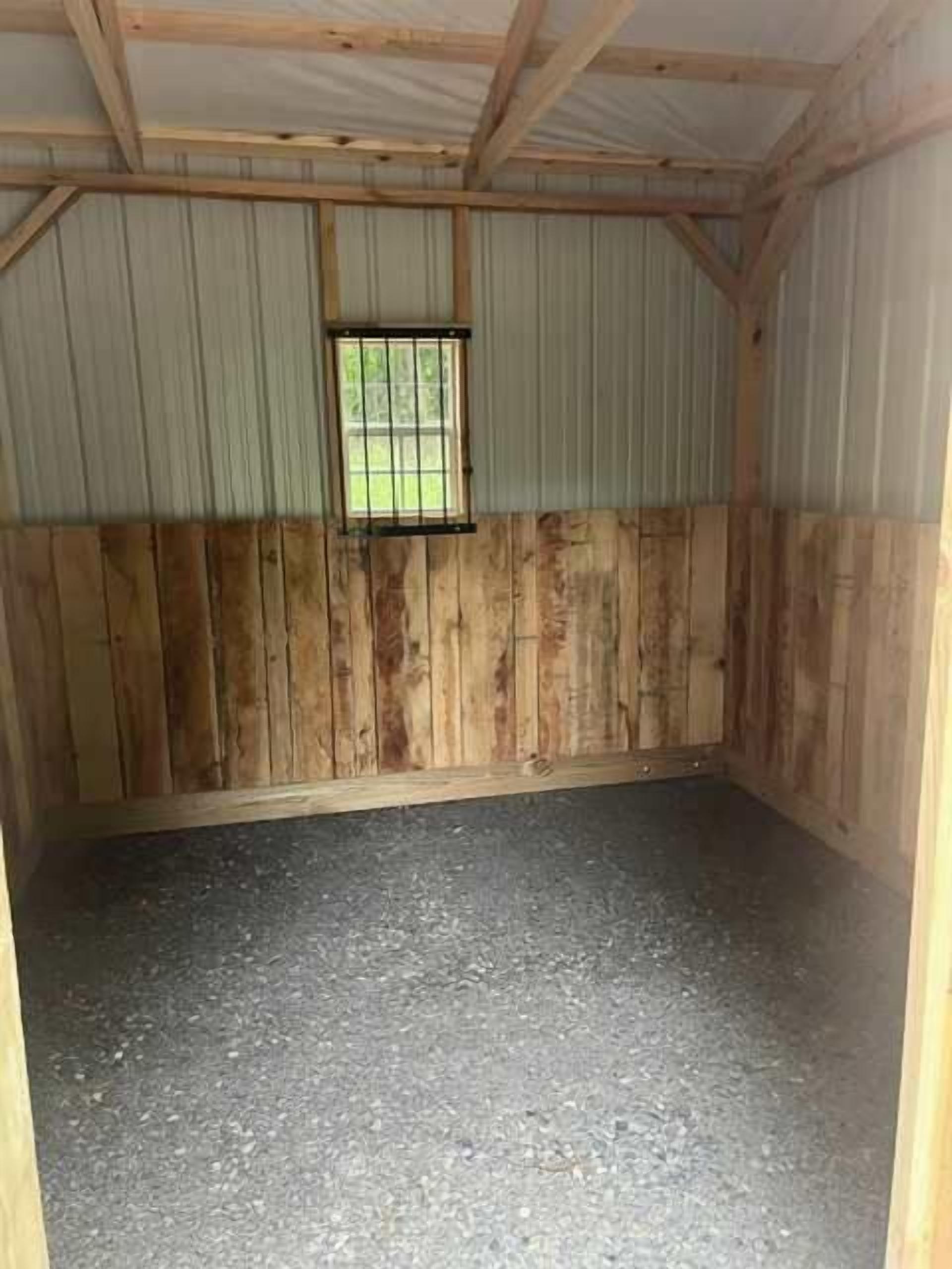 A room with a metal roof, wooden walls, a window, and a concrete floor.