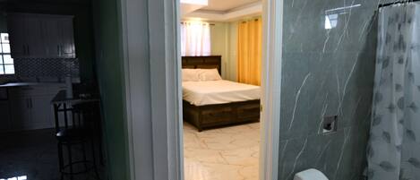 A hotel room with a bed, a bathroom, and a kitchenette.