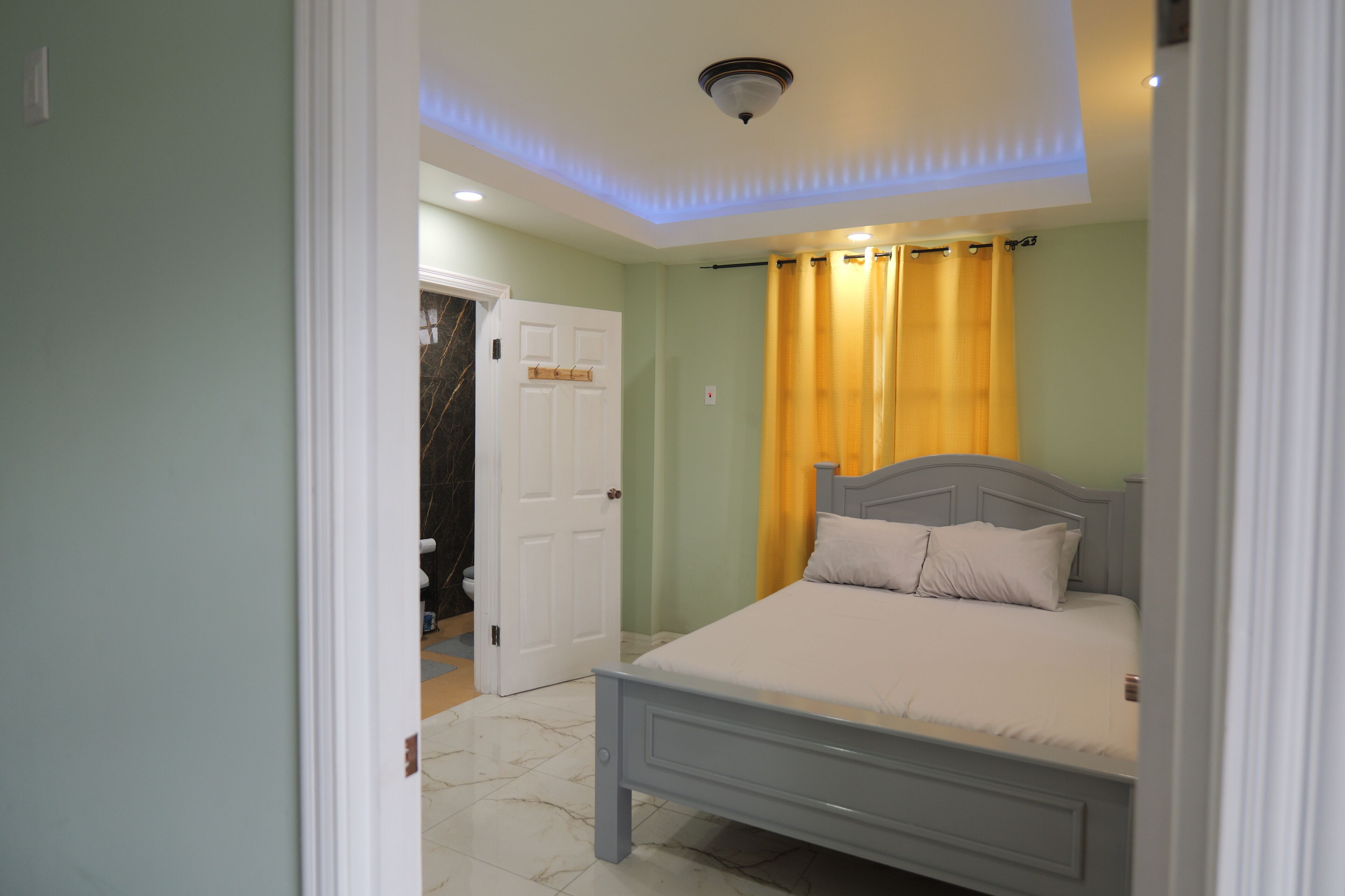 Un dormitorio con una cama, una puerta y un baño visible a través de otra puerta abierta.