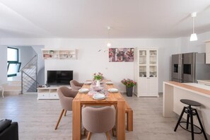 A modern living room with a dining table, chairs, a TV, and a kitchen area with a fridge and cabinets. - Spacious 5-bedroom apartment in marvelous Milna Hvar with AC (Milna Hvar)